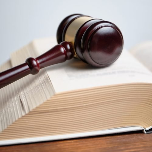 The judge hammer is next to the abstract book of the law